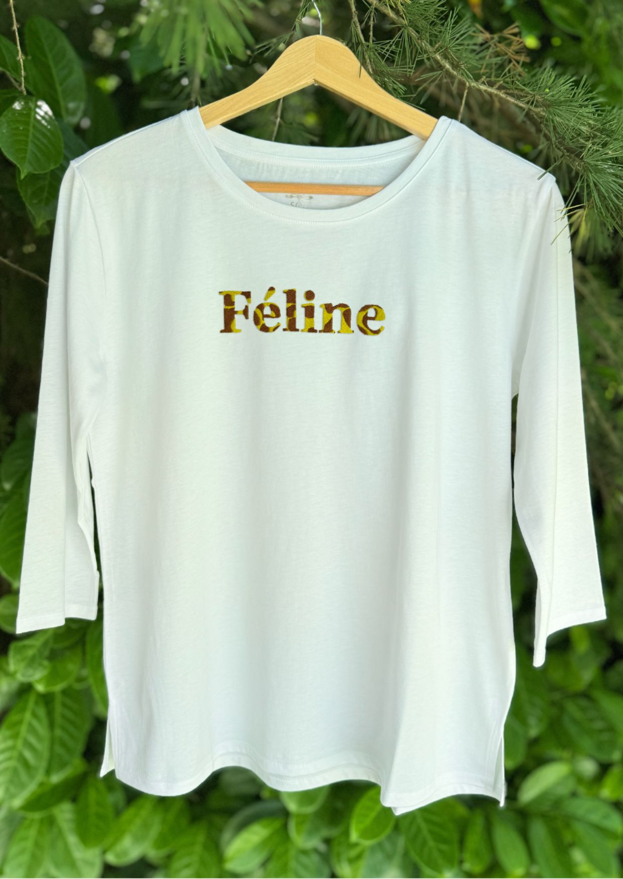 Tee-shirt manches 3/4 à col rond. Motif brodé lettres Féline avec griffe brodée. 100% coton biologique, confectionné au Portugal. Coupe évasée et fentes sur le côté. Grammage 150 gr/m2. Colori blanc.
