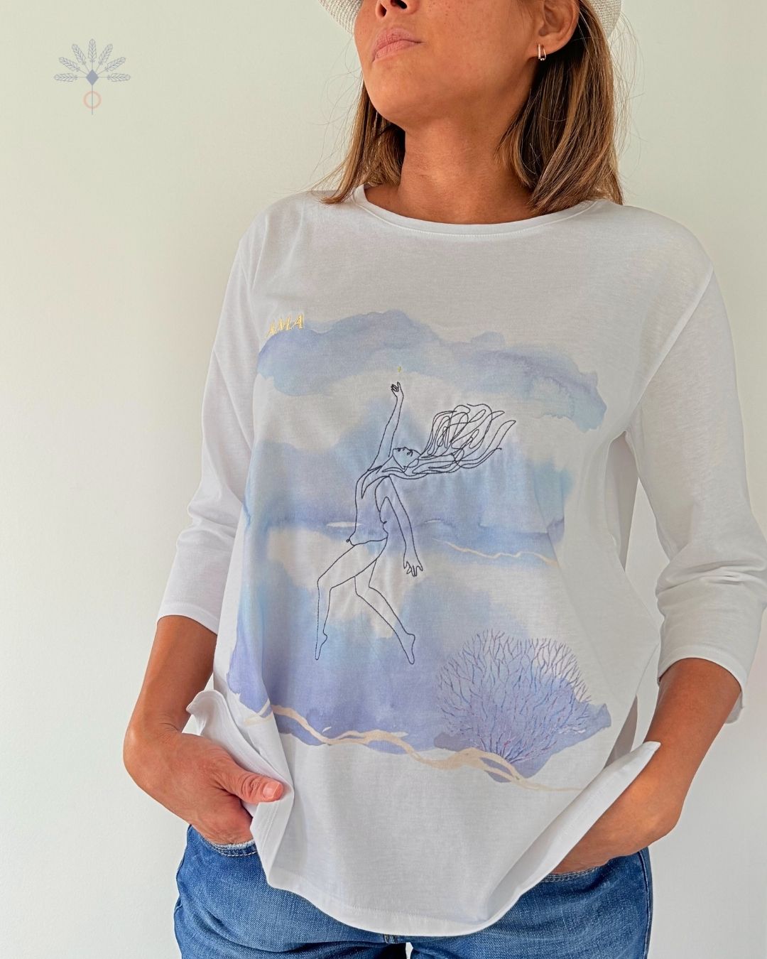 Tee-shirt Soamarena AMA porté par une femme, en coton biologique blanc, avec motif artistique bleu inspiré du mouvement et broderie discrète.